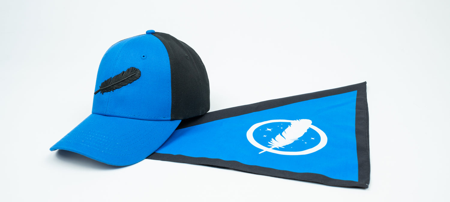 A blue and black cap with a feather logo beside a matching blue triangular flag with a feather emblem.