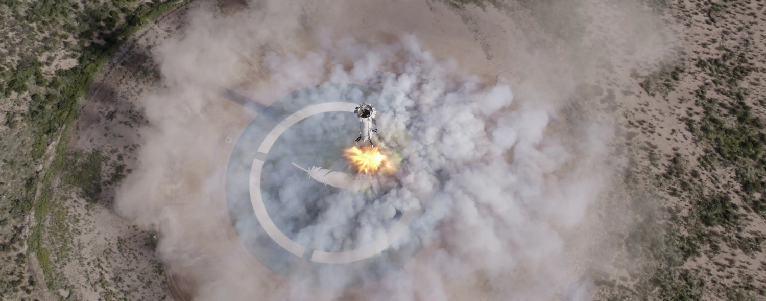 New Shepard booster landing, surrounded by thick smoke. The scene is vibrant and dynamic, with a clear circular pad and sparse vegetation visible.